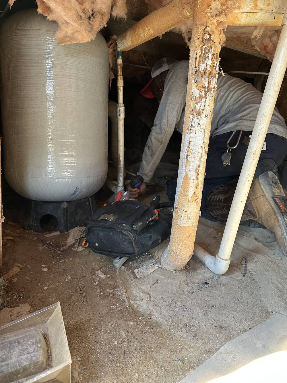 H&H technician working on a pressure tank under a house
